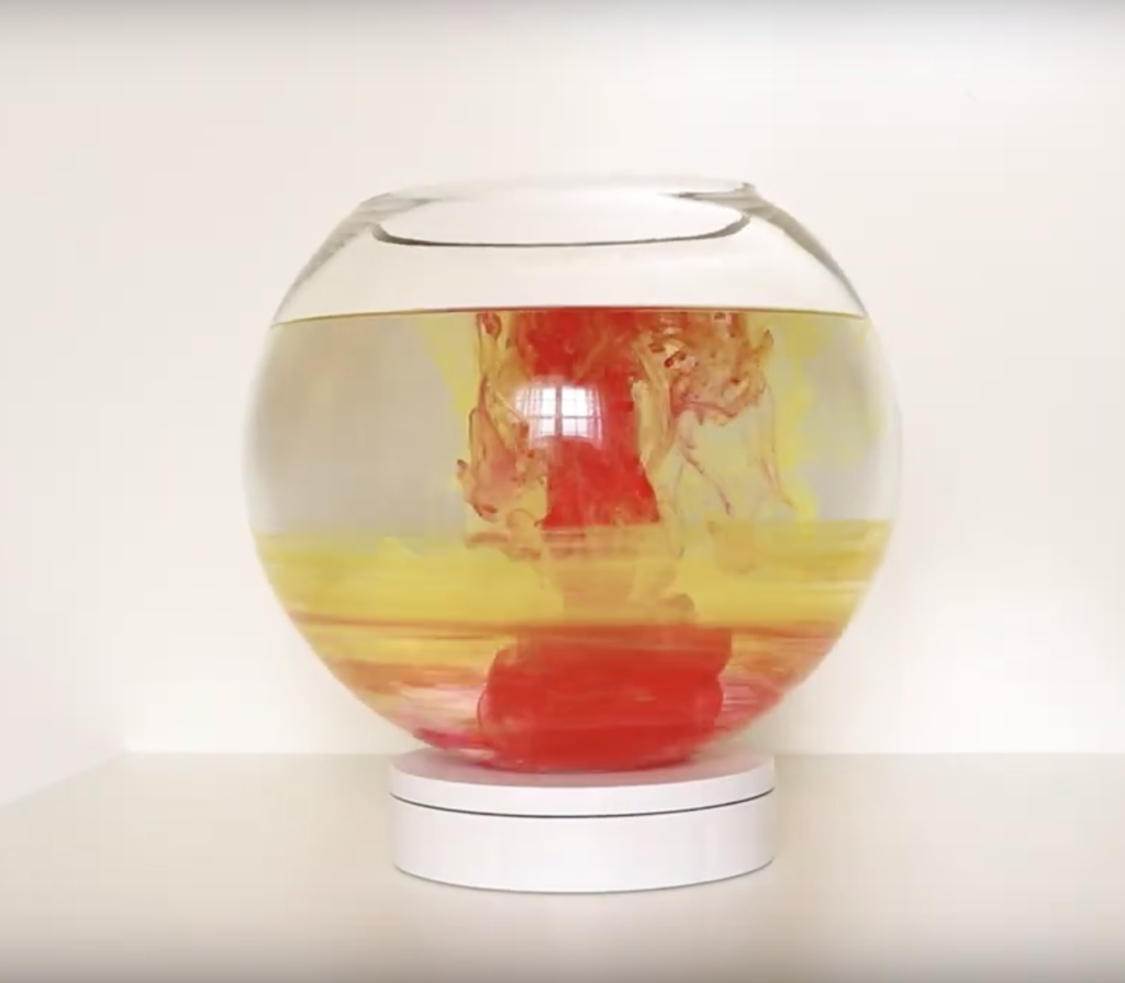 Fish bowl with red and yellow ink creating swirls like Jupiter.