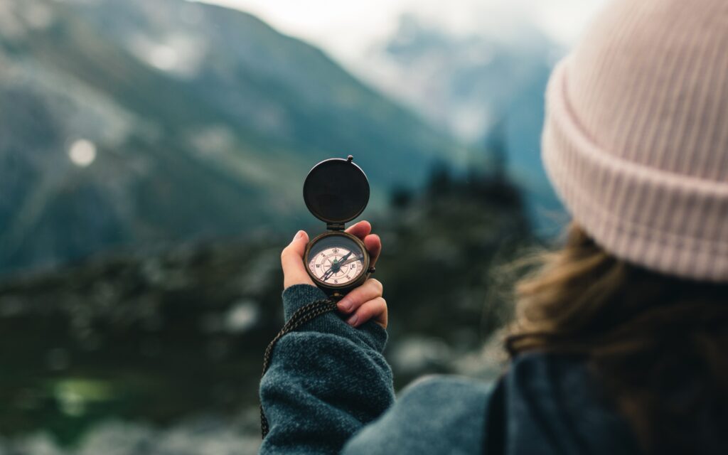 Hand holding compass with mountain in the distance