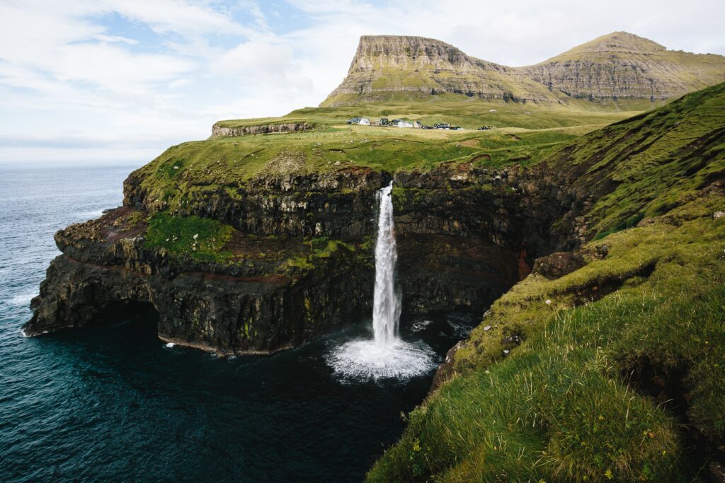 Aerial photo of waterfall from a green island into the ocean