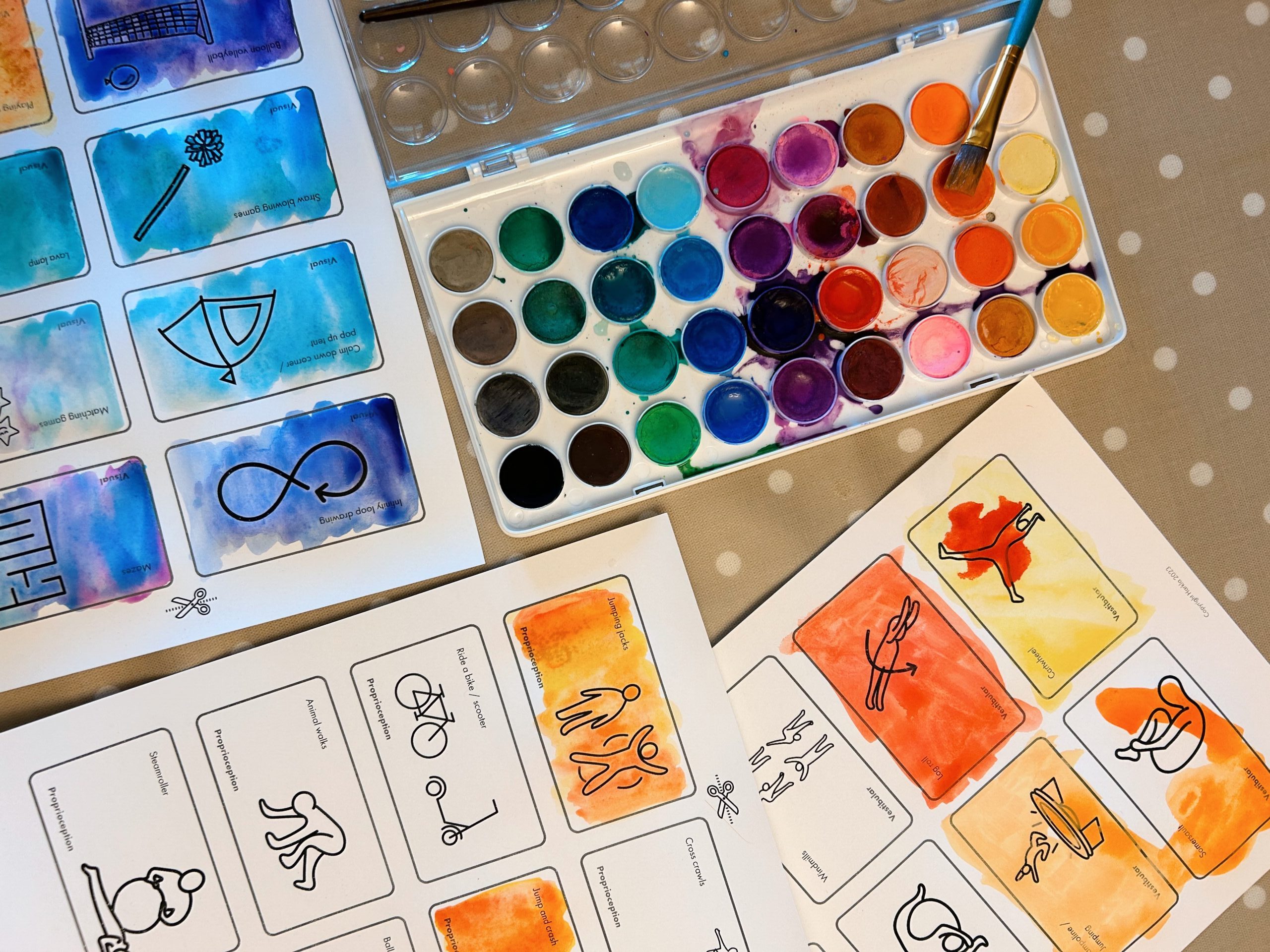 Watercolor cards with sensory supports and spread out on a table with art supplies