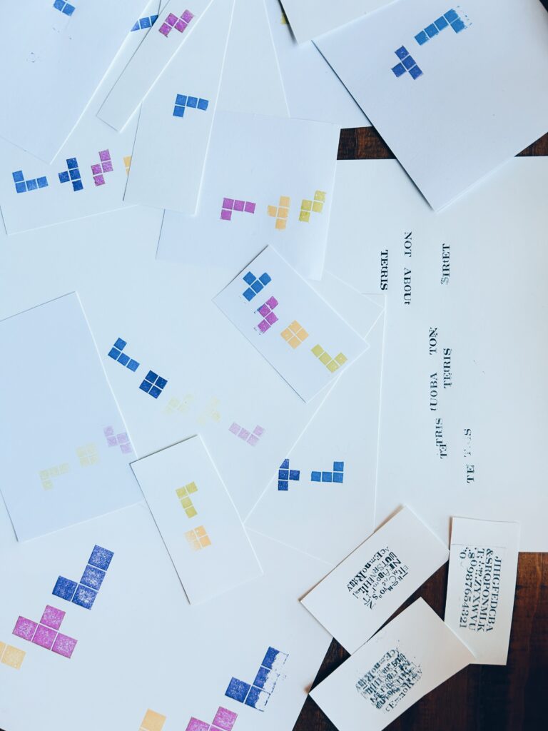 Prints of TETRIS shapes made with flat LEGO pieces and letterpress cover the table