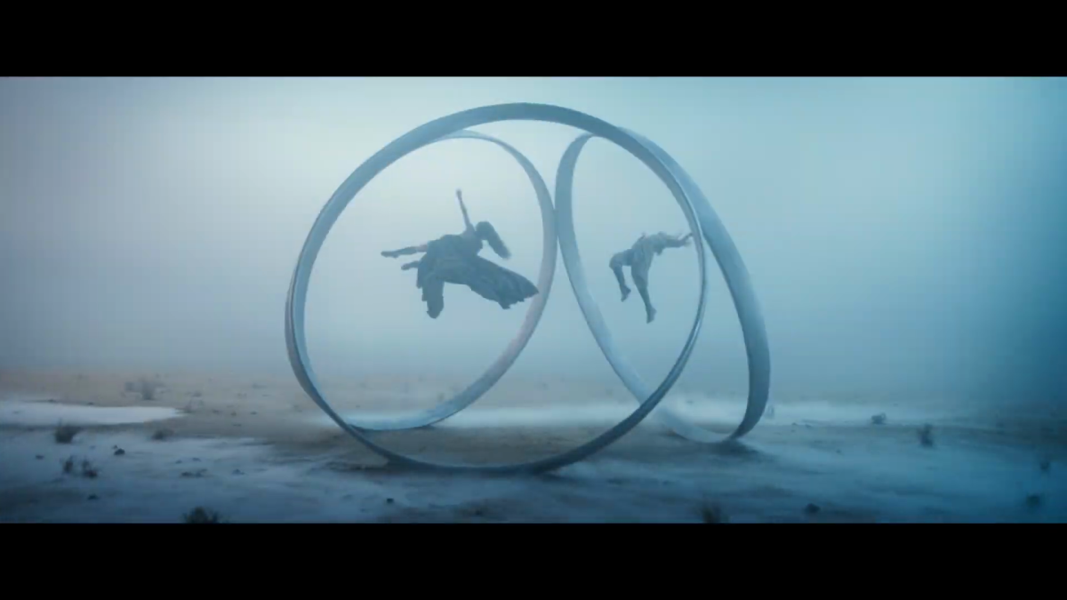 A misty location with two figures suspended within three silver rings