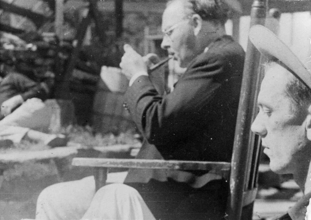 Black and white photograph of white man lighting pipe