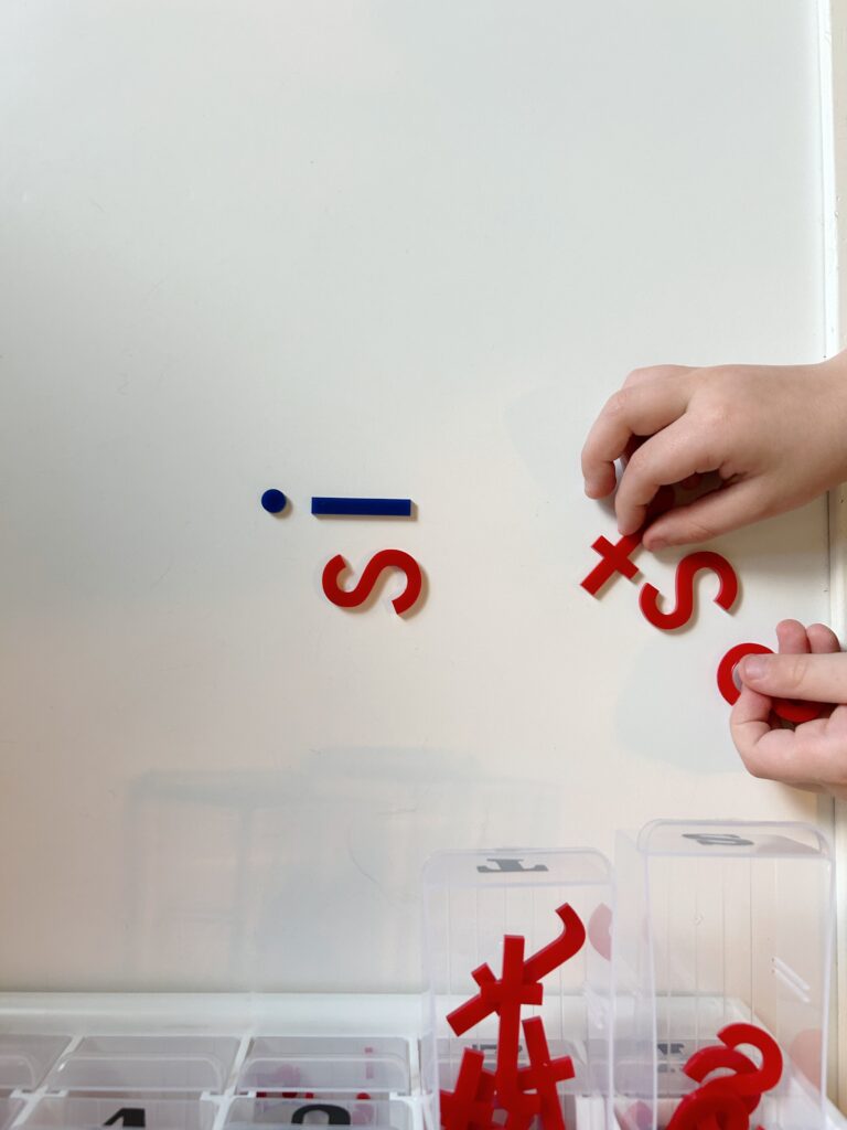 Montessori alphabet hands are moving letters to spell sit