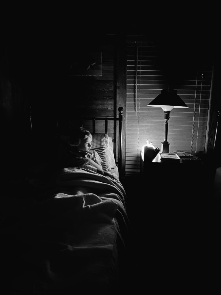 Black and white photograph of nightlight  and lamp in a dark cabin room.