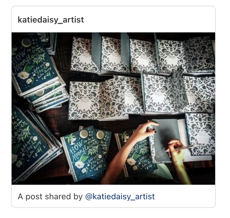 Katie Daisy signing How to Be a Moonflower open books on a wooden table
