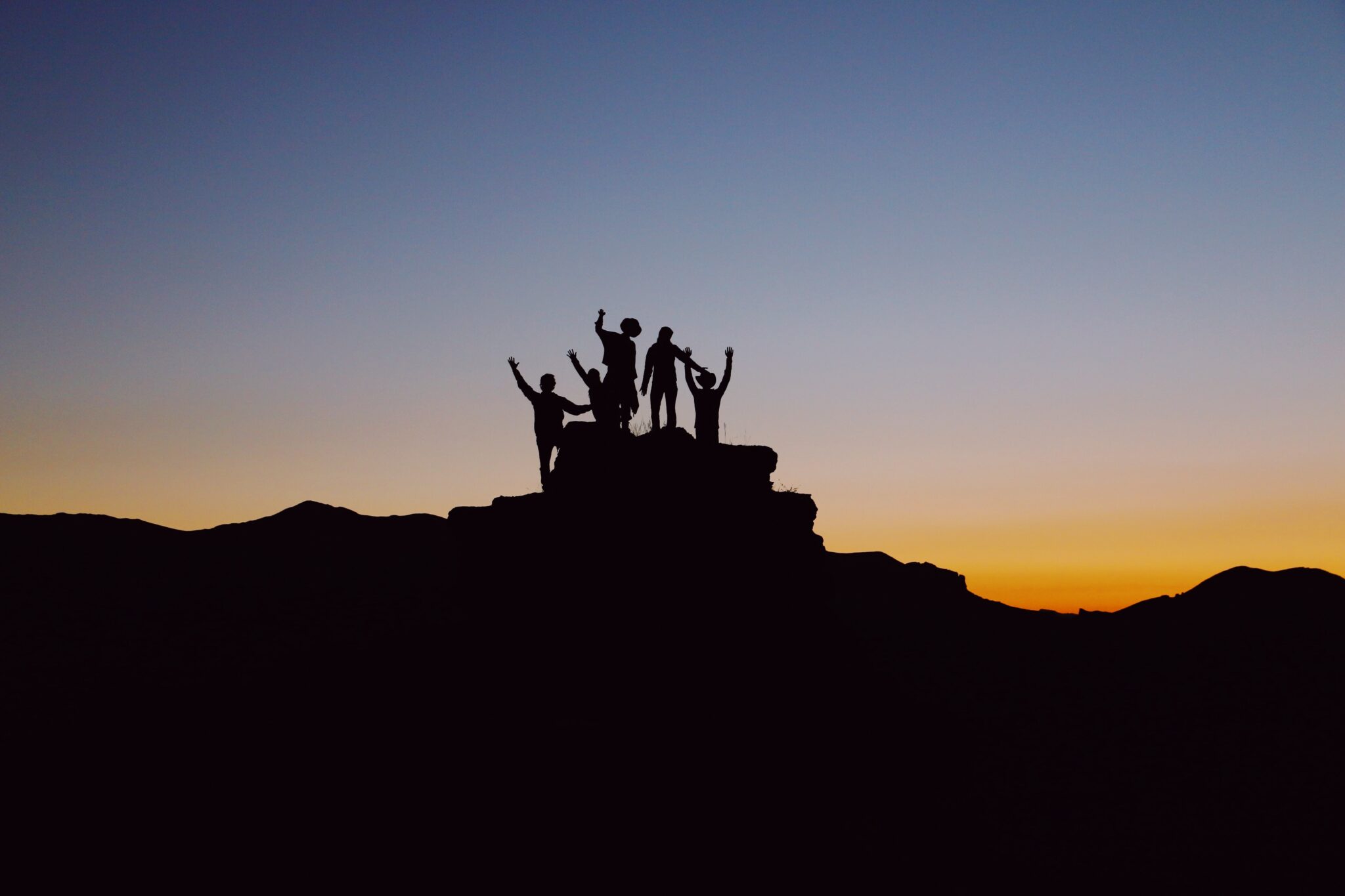 FIgures in silhouette on a plateau with a sunset behind