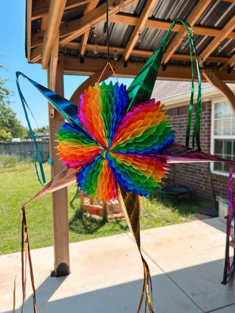 Star shaped rainbow piñata hanging from the patio