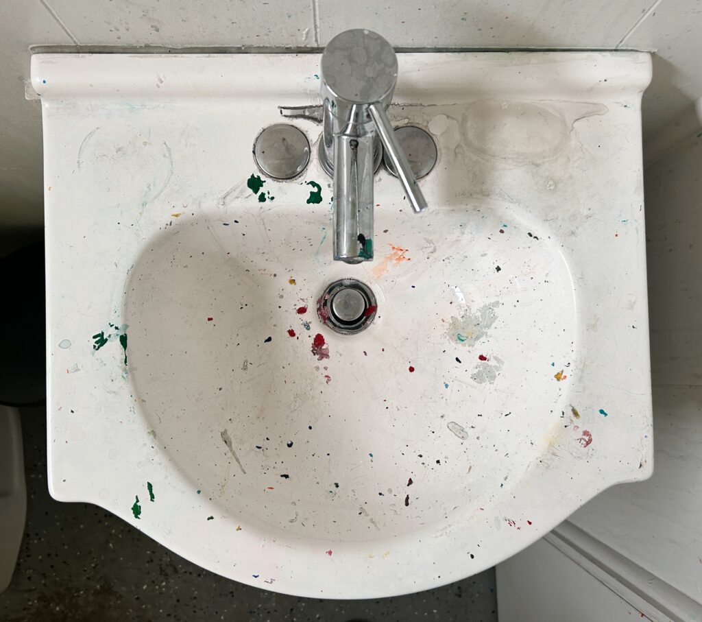 White sink with colorful paint spatters.