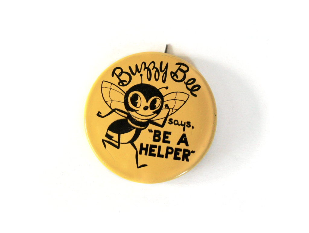 Yellow vintage circular button with a black bee illustrated on it and the words Buzzy Bee says, "Be a helper."