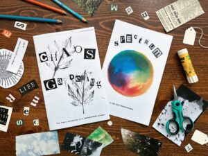 Two zines and magazine clippings on a wooden desk with scissors, gluestick and pencils. Both zines titles are cut out magazine letters: Chaos Gardening with leaf rubbings and Spectrum with a hand painted watercolor color wheel.