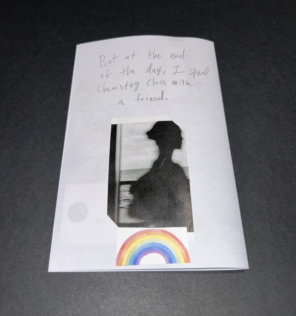 Back cover. Handwriting reads: But at the end of the day I sit in chemistry class with a friend. A black and white silhouette of a figure before a window is glued to the page and below it a rainbow.
