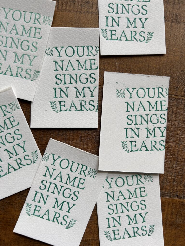 Tiny off centered test prints of letterpress style Your name sings in my ears quotes with leaf motif.