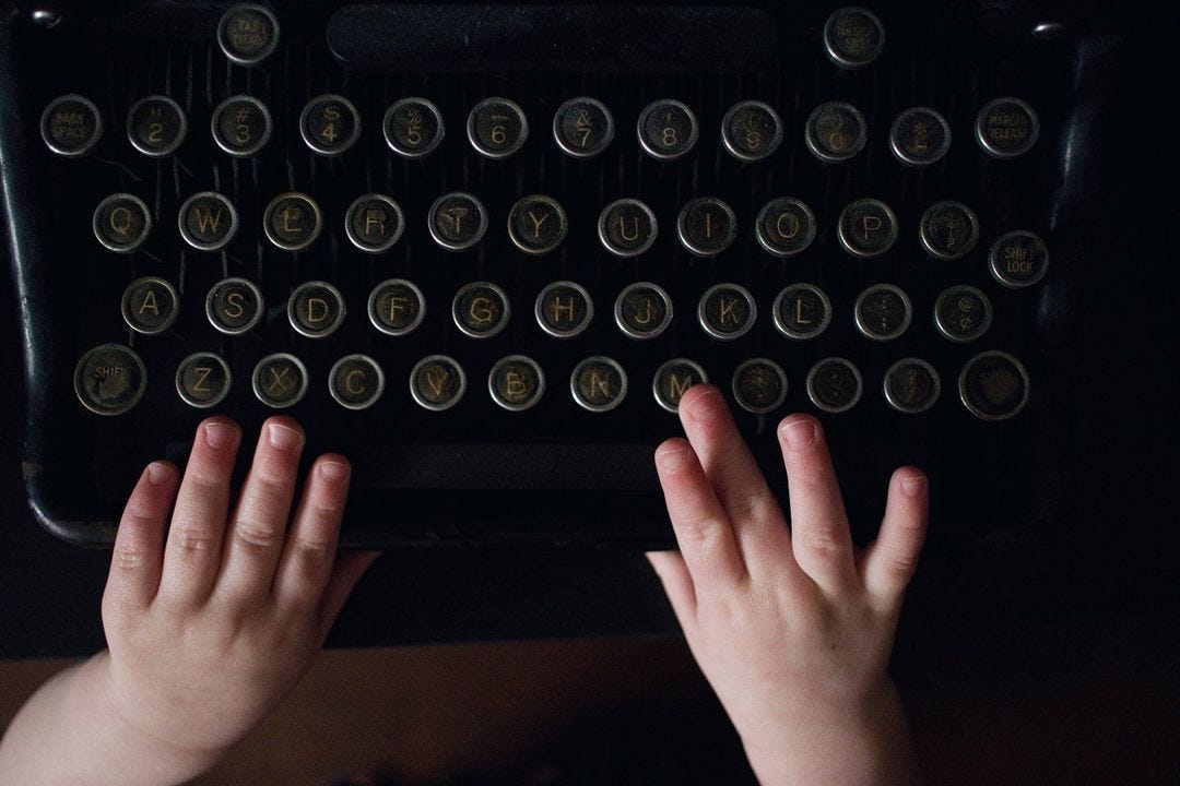 Tiny toddler hands reaching toward keys on a vintage typewriter