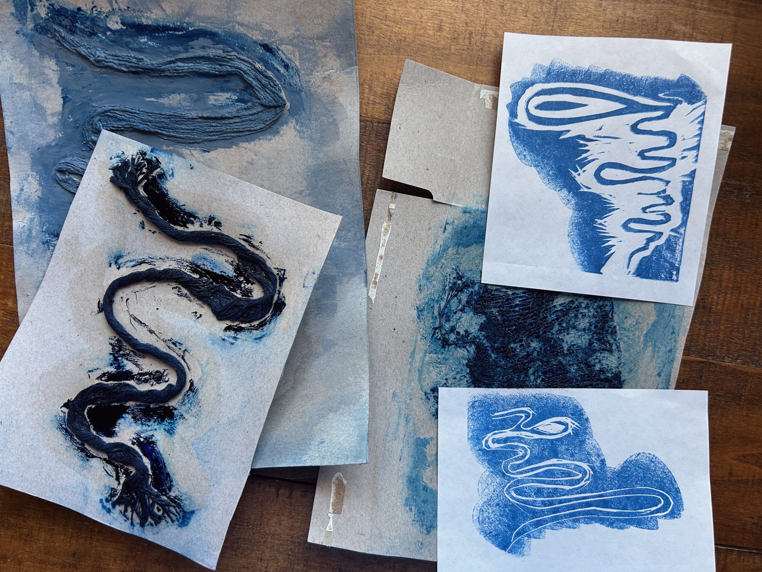 Test prints and collograph plates of a meandering river with blue ink