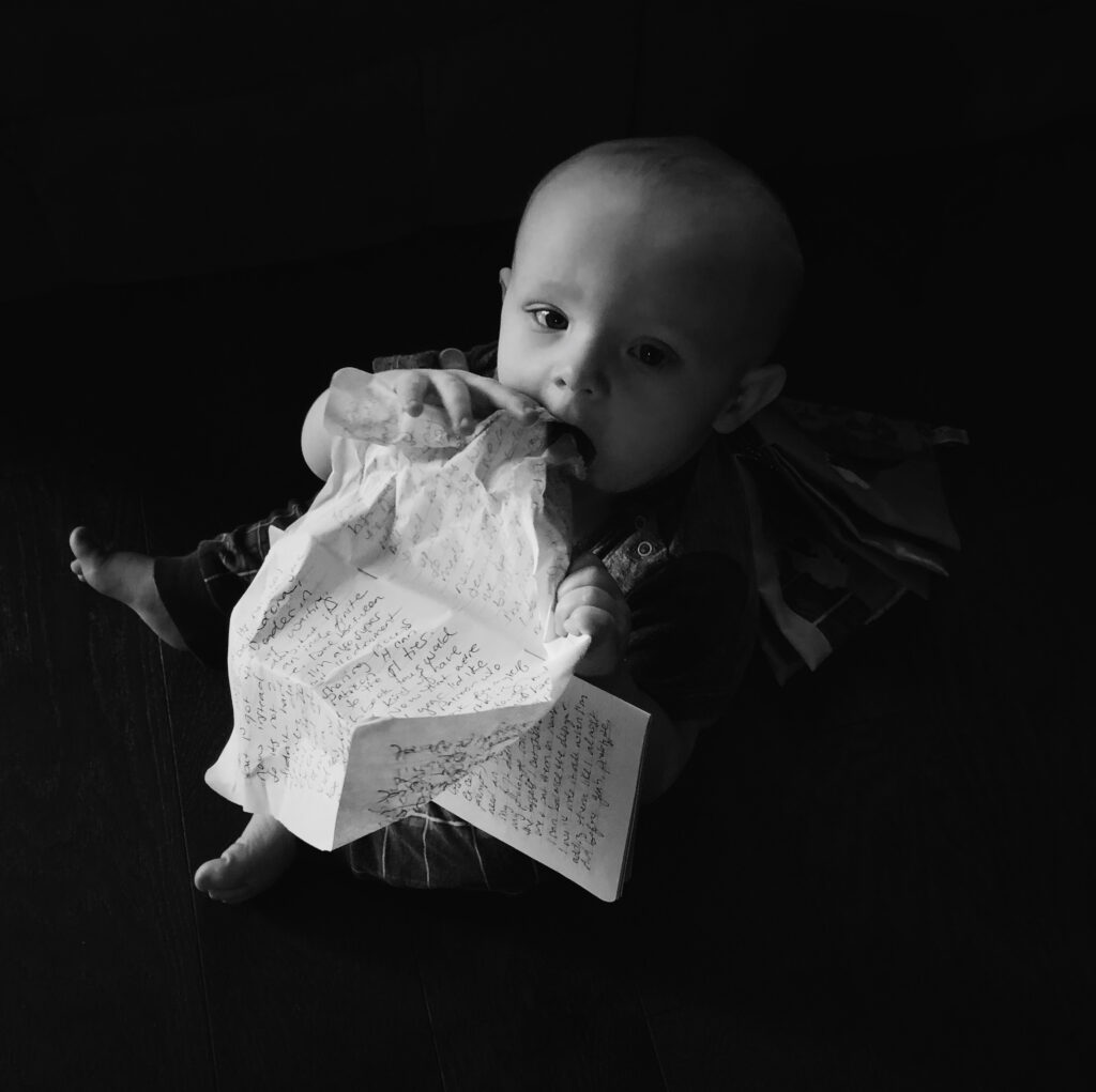 Black and white photo of an infant chewing on my journal entry. I think this was a month or two before they started walking so almost a toddler, but not quite.