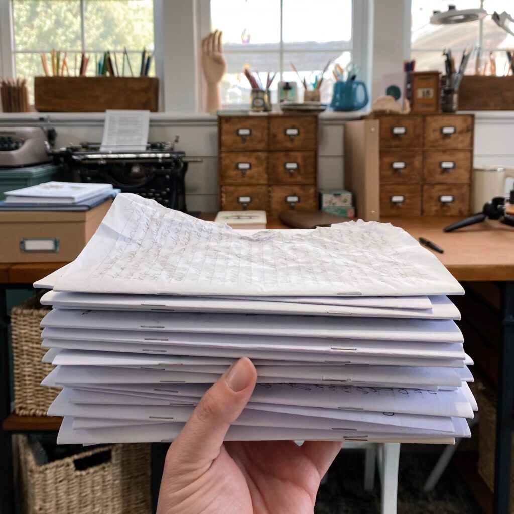 Holding a stack of journaling inserts in my art studio. The top one is rumpled.