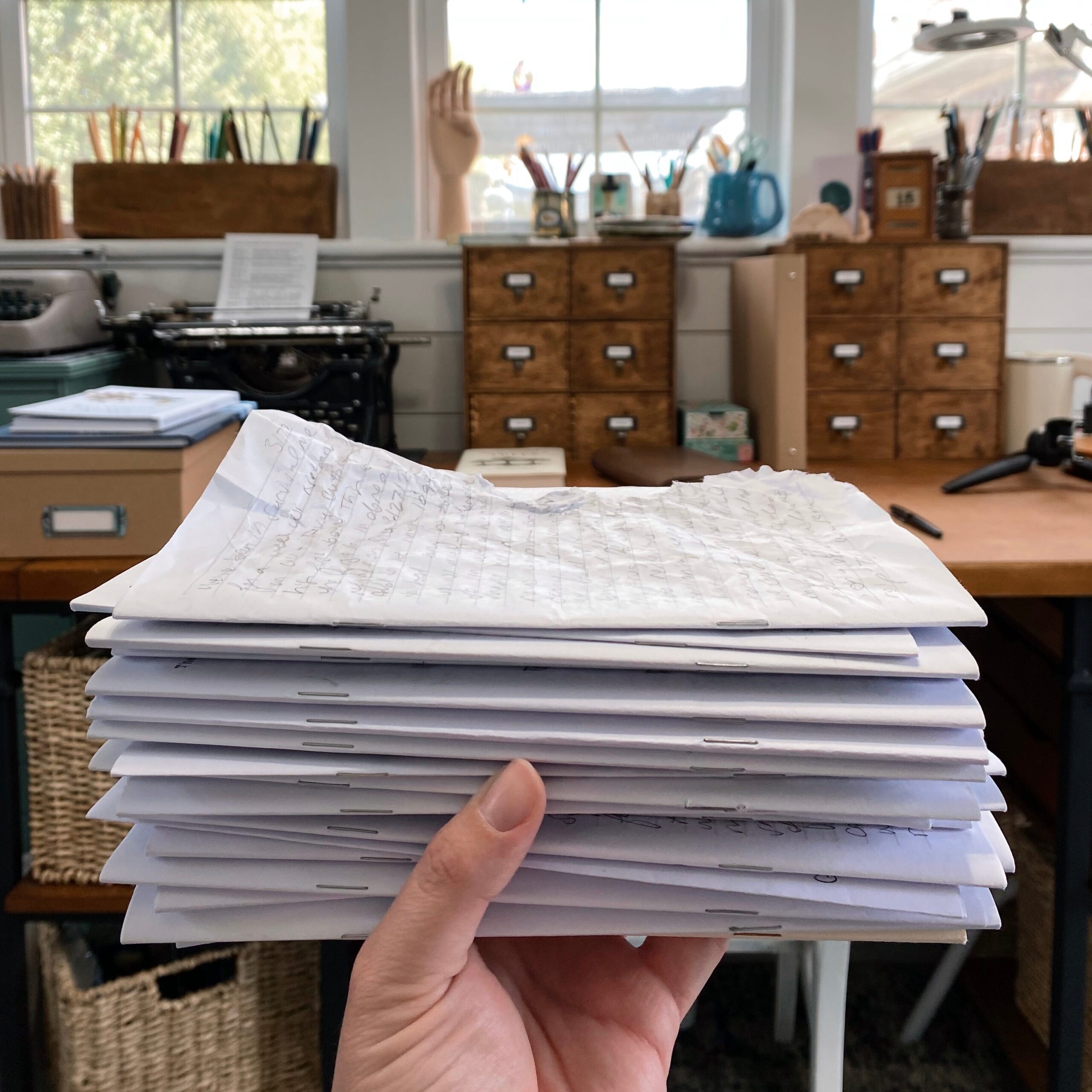 Holding a stack of journaling inserts in my art studio. The top one is rumpled.