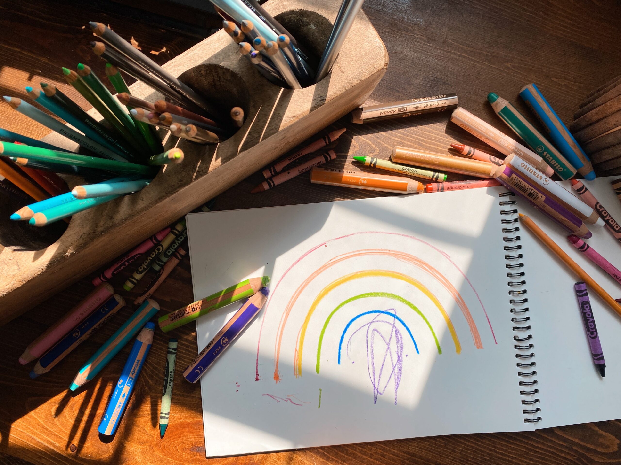 Sketchbook with rainbow surrounded by art supplies
