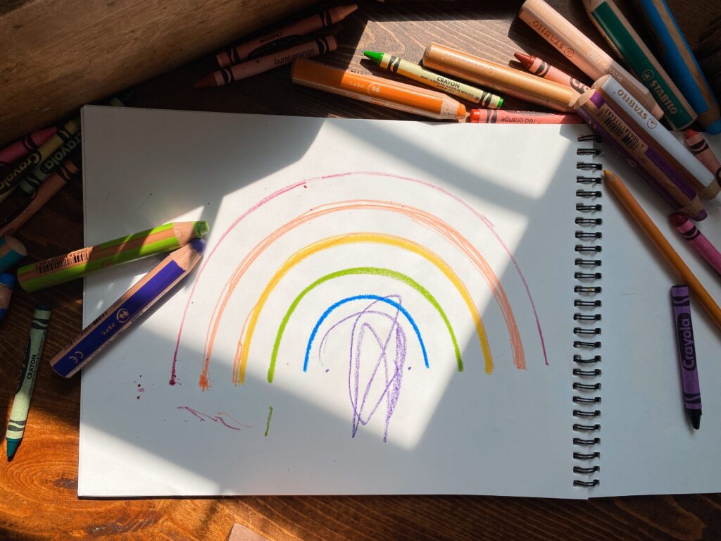 Sketchbook with rainbow surrounded by art supplies